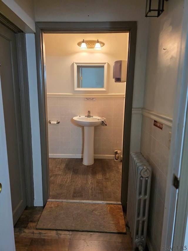218 Center St, Meyersdale, PA 15552 - bathroom featuring wood finished floors, a sink, tile walls, wainscoting, and radiator heating unit
