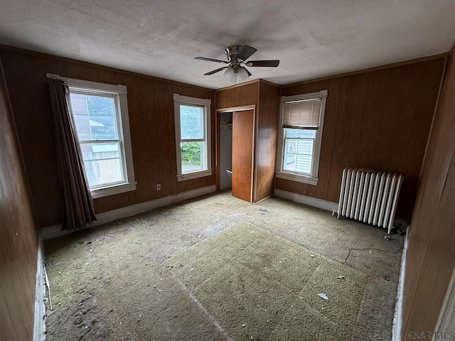 717-719 Messenger St, Johnstown, PA 15902 - unfurnished bedroom featuring radiator heating unit, a textured ceiling, wood walls, ceiling fan, and a closet
