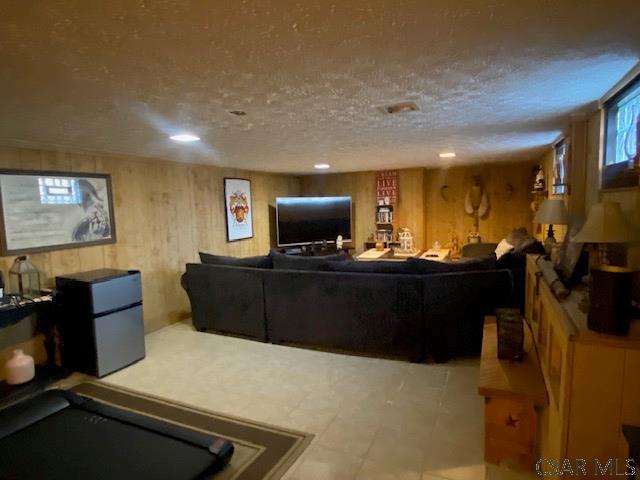 living room featuring wooden walls and a textured ceiling