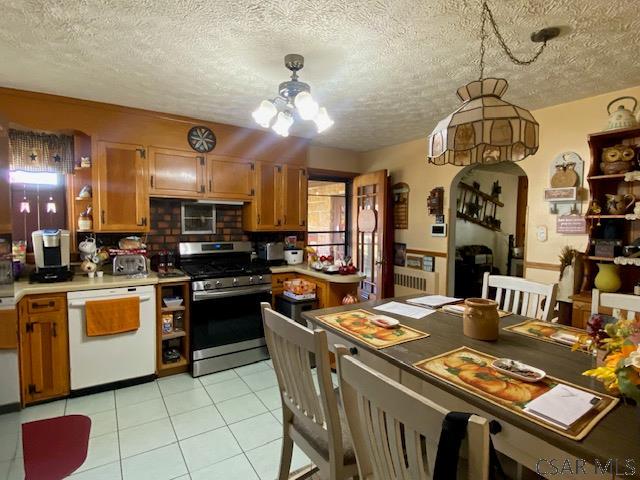 kitchen with hanging light fixtures, a textured ceiling, stainless steel gas range, and dishwasher