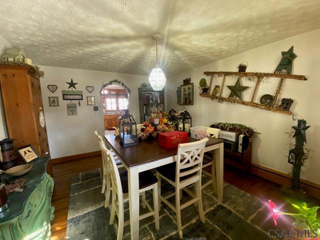 dining space with a textured ceiling and dark hardwood / wood-style flooring