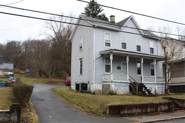 view of front facade with central AC, a front yard, and covered porch