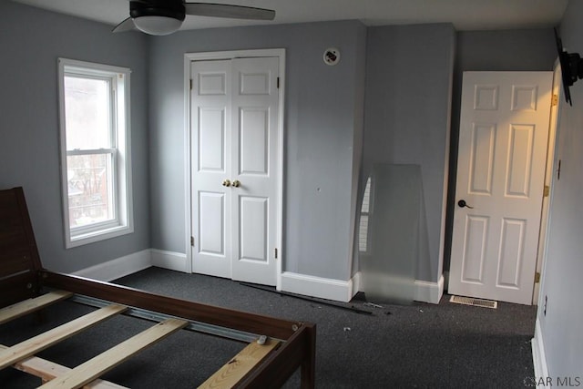 unfurnished bedroom with dark carpet, ceiling fan, and a closet