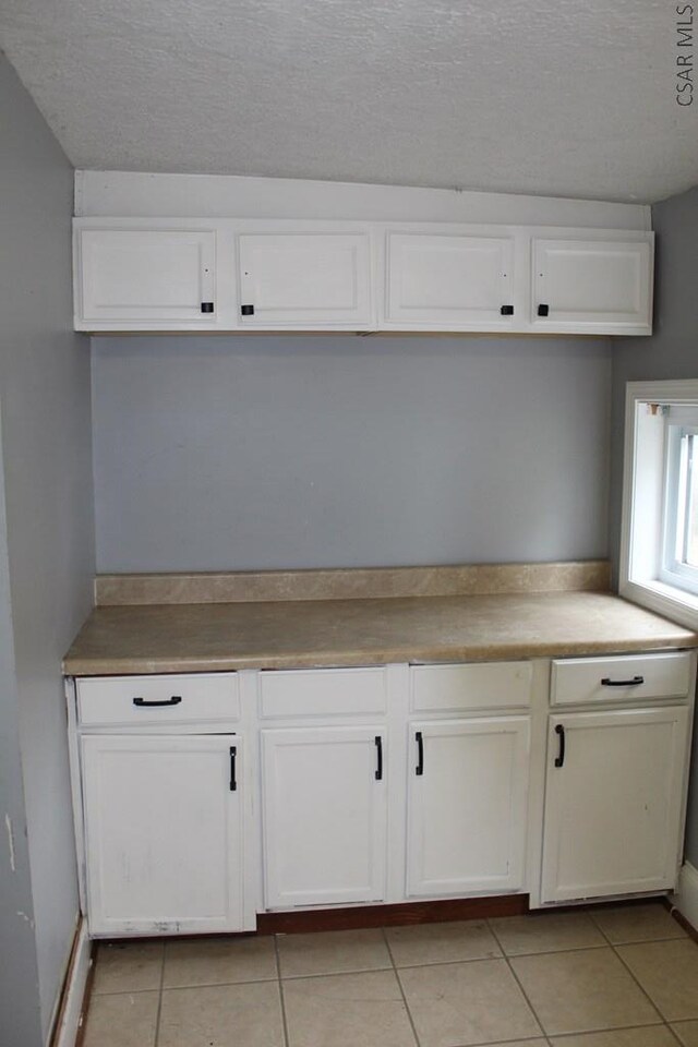 kitchen with white cabinets, a textured ceiling, and light tile patterned floors