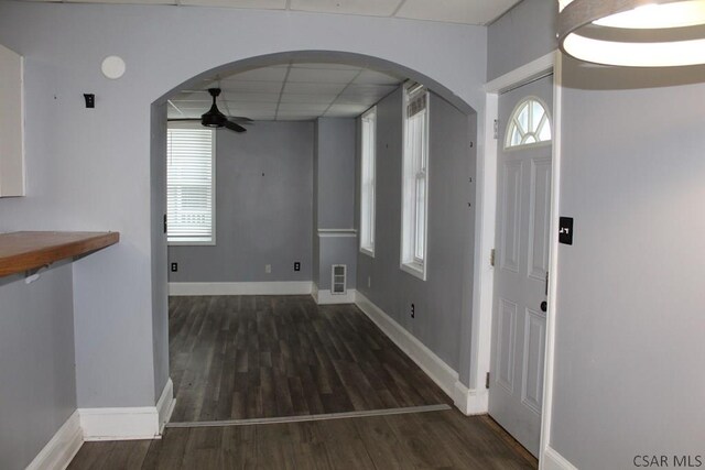 interior space featuring dark hardwood / wood-style flooring, a drop ceiling, and ceiling fan