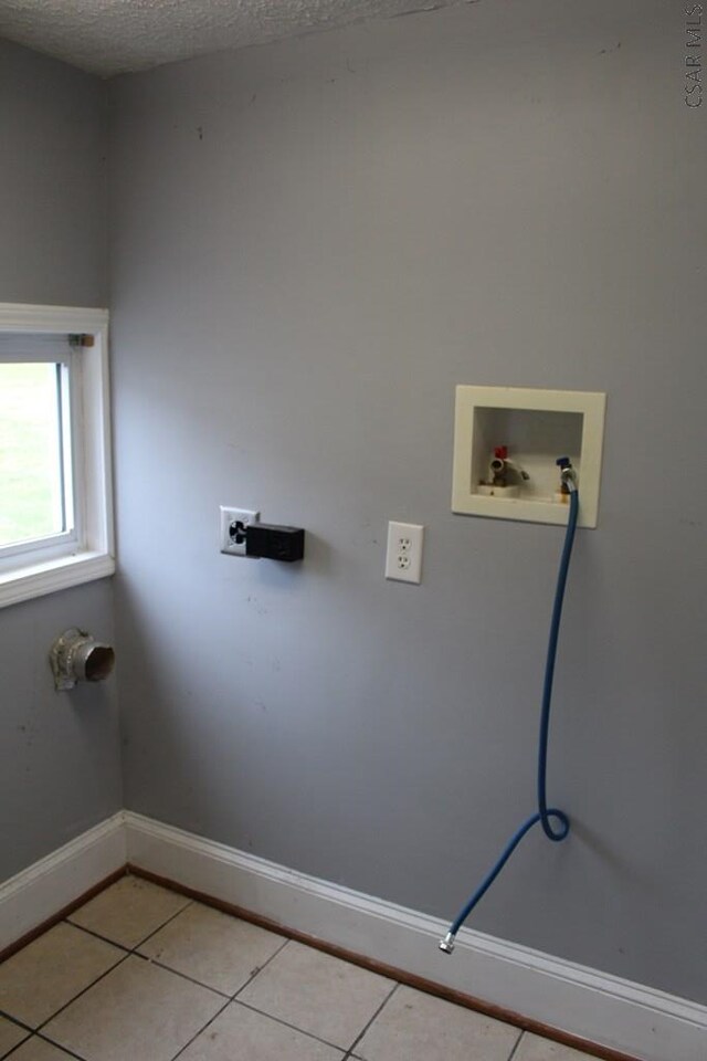 clothes washing area featuring light tile patterned floors, hookup for a washing machine, and a textured ceiling