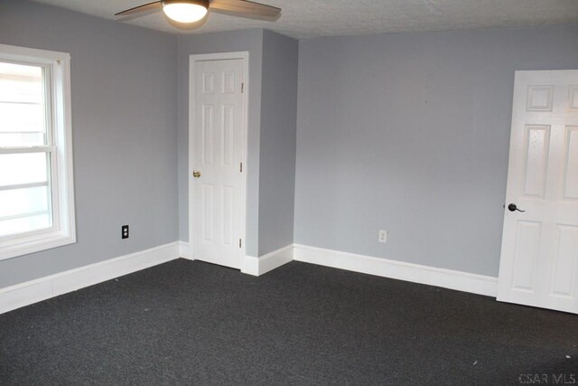 carpeted spare room featuring ceiling fan and plenty of natural light