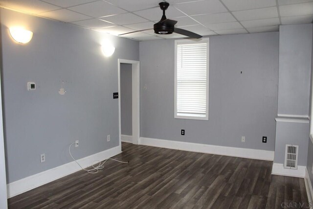 unfurnished room featuring dark wood-type flooring, ceiling fan, and a drop ceiling