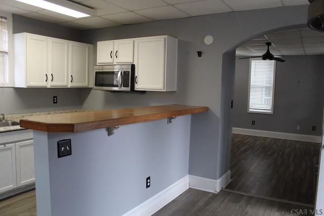 kitchen with white cabinetry, dark wood-type flooring, a paneled ceiling, and kitchen peninsula