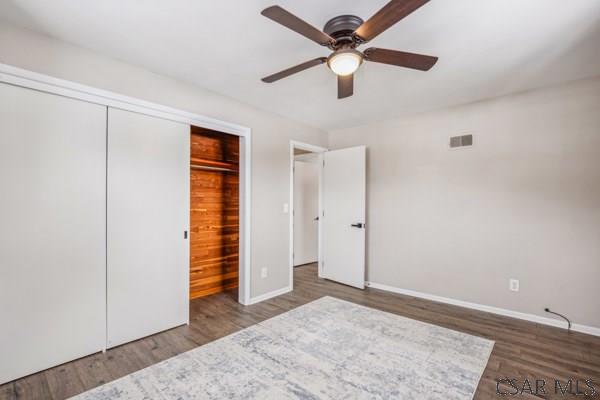 unfurnished bedroom with dark wood-type flooring, ceiling fan, and a closet