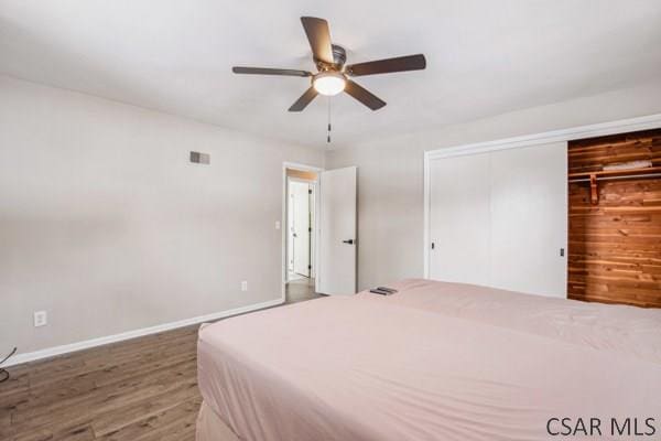 bedroom featuring dark hardwood / wood-style floors, ceiling fan, and a closet