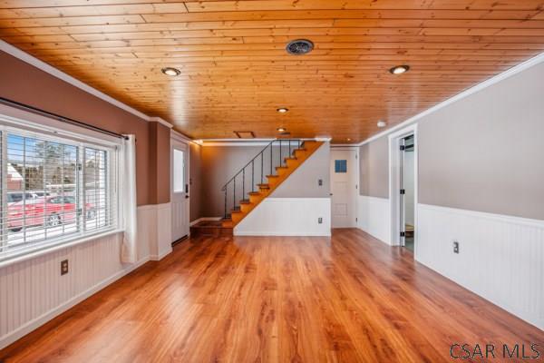 entryway with a brick fireplace, wood ceiling, wood-type flooring, and ornamental molding