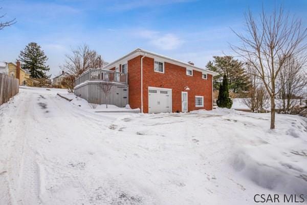 snow covered property featuring a wooden deck and a garage