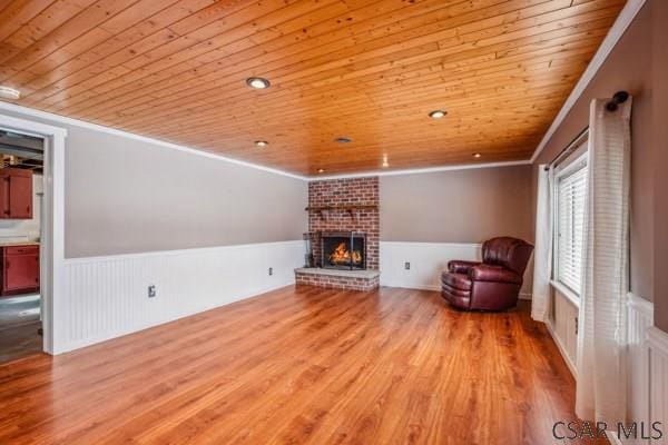 unfurnished living room featuring ornamental molding, a fireplace, wood ceiling, and light hardwood / wood-style flooring