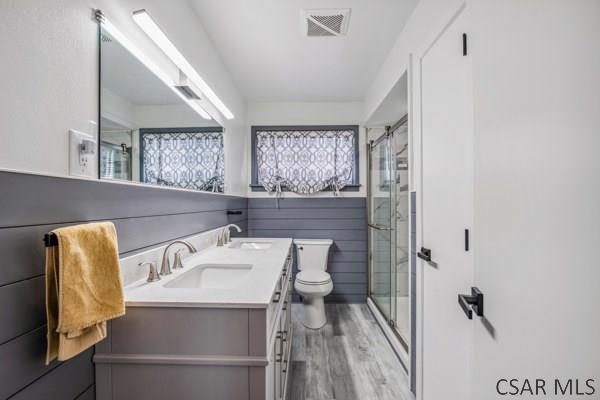 bathroom featuring vanity, wood-type flooring, a shower with door, and toilet