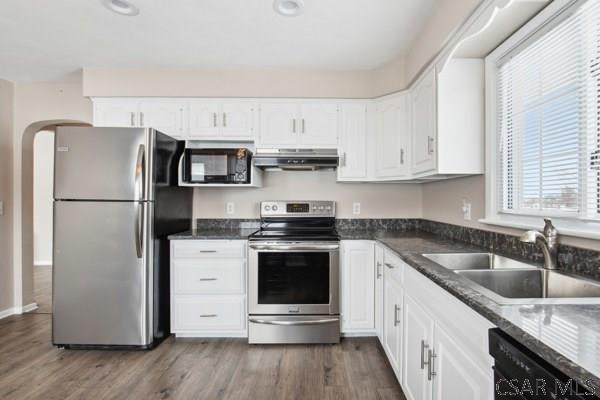 kitchen with dark stone countertops, sink, stainless steel appliances, and white cabinets