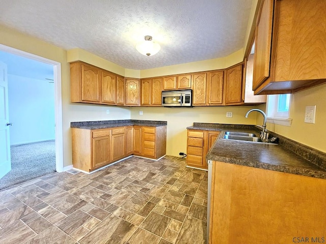 kitchen featuring dark carpet, sink, and a textured ceiling