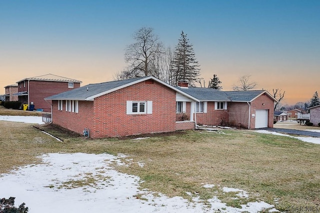 ranch-style home with an attached garage, brick siding, concrete driveway, a front lawn, and a chimney