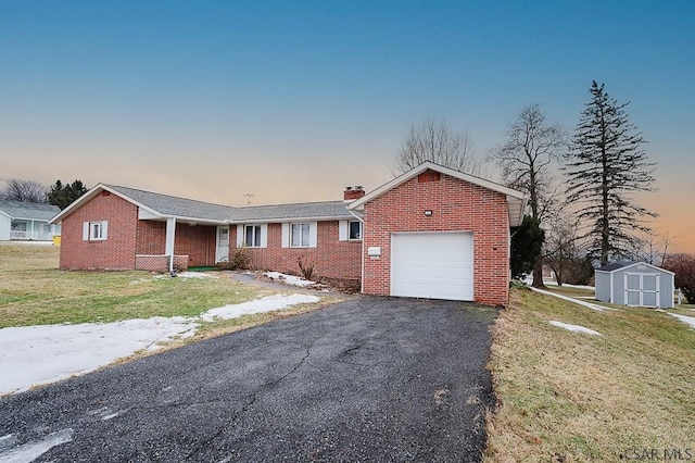 ranch-style home with aphalt driveway, brick siding, a chimney, a storage unit, and an attached garage