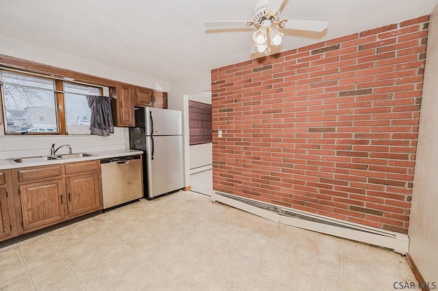 kitchen with brown cabinetry, a baseboard radiator, stainless steel appliances, light countertops, and a sink