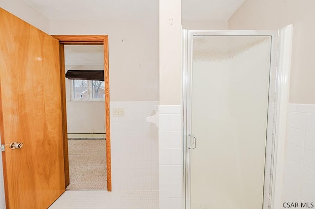 full bathroom with a shower stall, baseboard heating, tile walls, and wainscoting