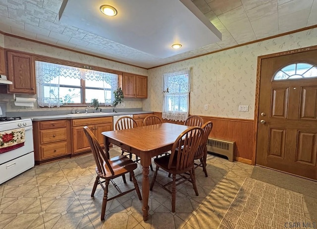 dining room with sink, radiator heating unit, ornamental molding, and wood walls