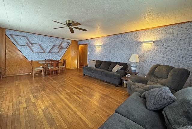 living room featuring crown molding, wooden walls, ceiling fan, and hardwood / wood-style flooring