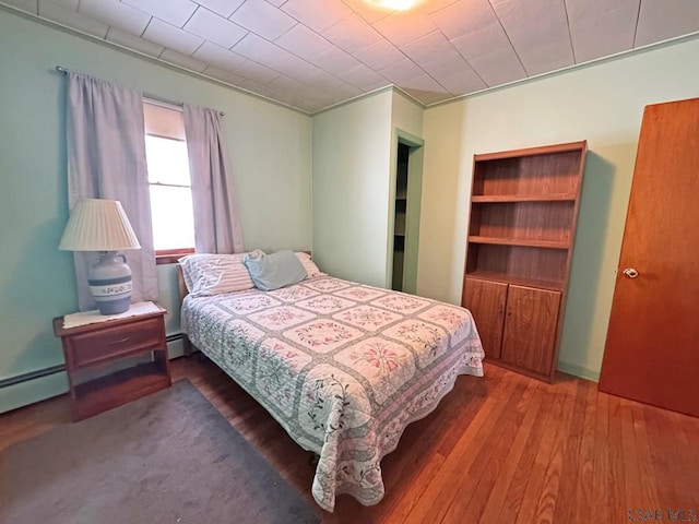 bedroom with wood-type flooring and a baseboard radiator