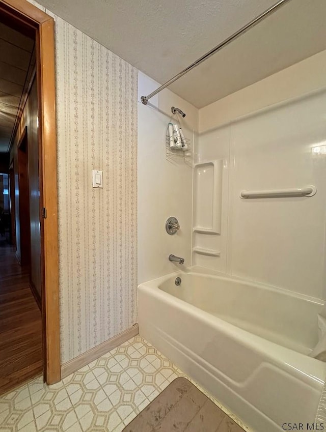 bathroom with washtub / shower combination and a textured ceiling