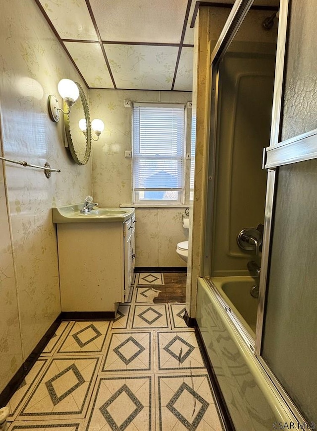 full bathroom with tile patterned floors, toilet, shower / bath combination with glass door, wallpapered walls, and vanity