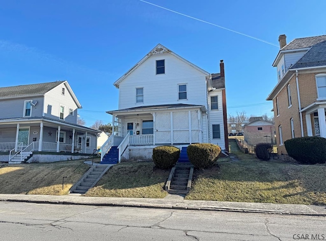 view of front of property featuring stairway, covered porch, and a front lawn