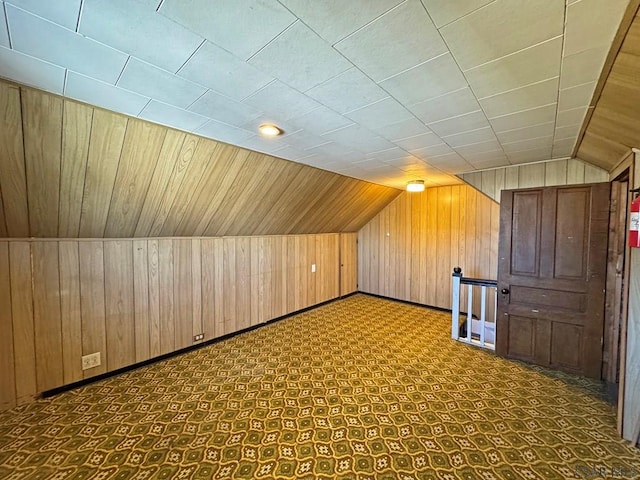 additional living space with wooden walls, baseboards, and lofted ceiling