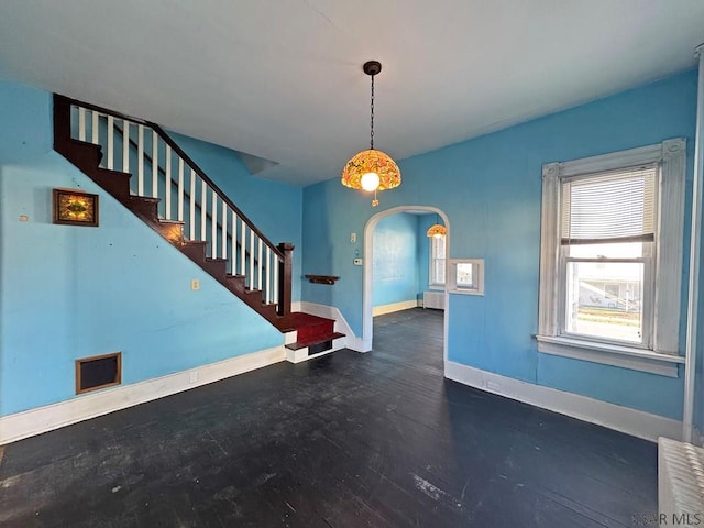 interior space featuring stairway, baseboards, and arched walkways