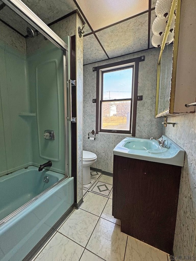 full bath with wallpapered walls, bath / shower combo with glass door, vanity, and toilet