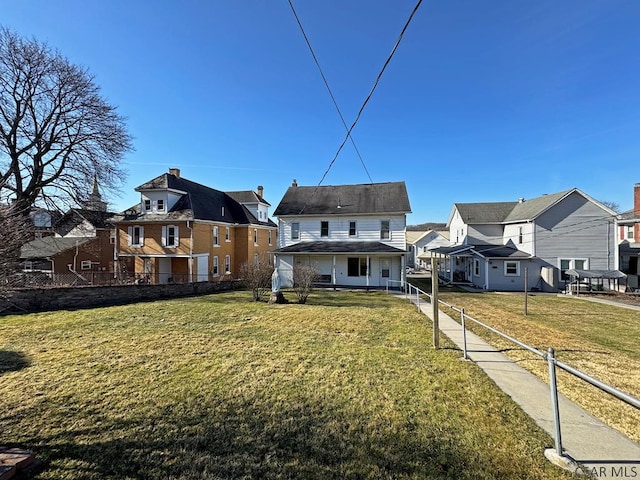 back of house featuring fence, a residential view, and a lawn