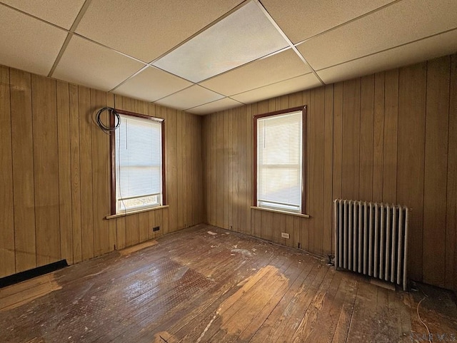 spare room featuring a drop ceiling, plenty of natural light, radiator, and hardwood / wood-style floors