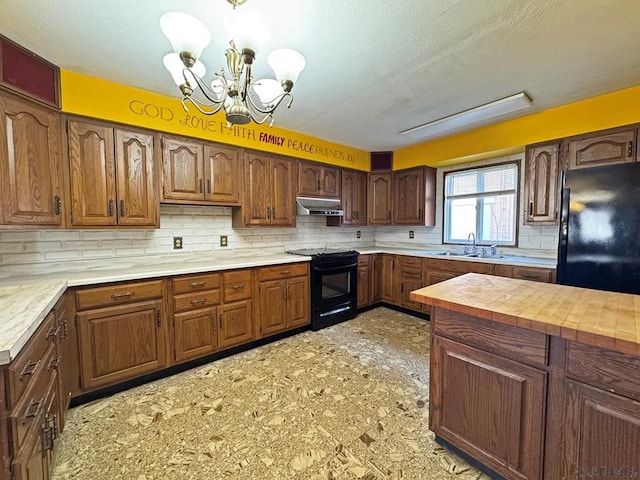 kitchen with an inviting chandelier, a sink, black appliances, under cabinet range hood, and tasteful backsplash