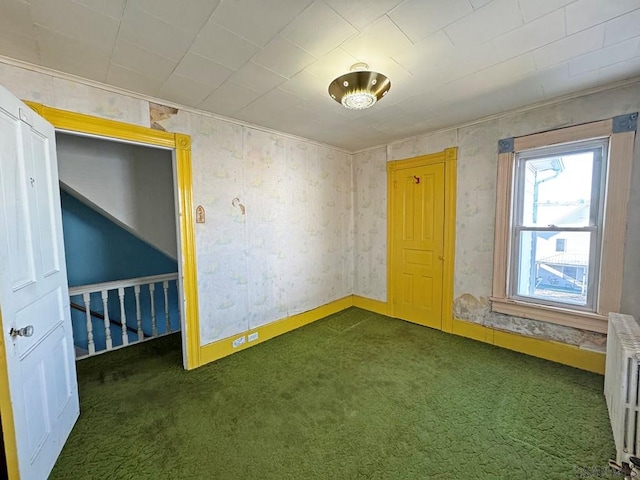 empty room with radiator heating unit, baseboards, and carpet floors