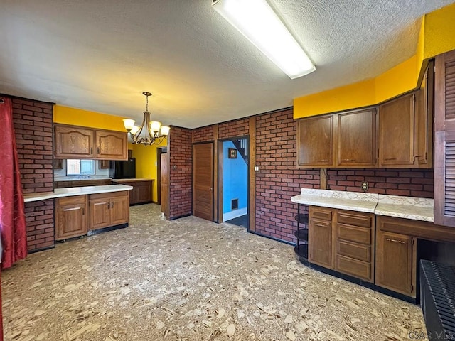 kitchen featuring a chandelier, brick wall, a textured ceiling, and light countertops