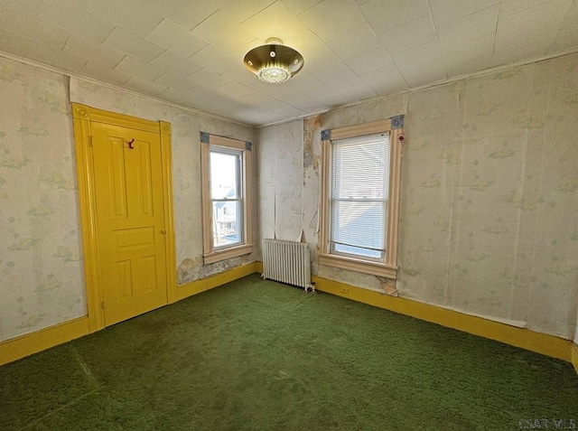 unfurnished room featuring dark carpet, radiator heating unit, and baseboards