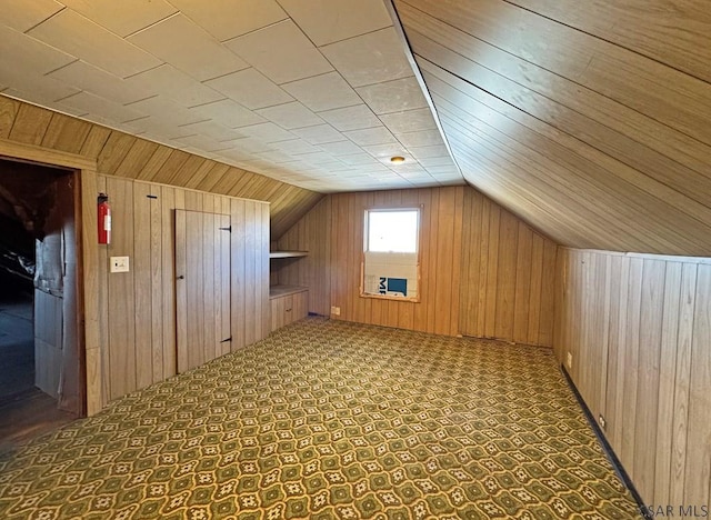 bonus room featuring vaulted ceiling and wood walls