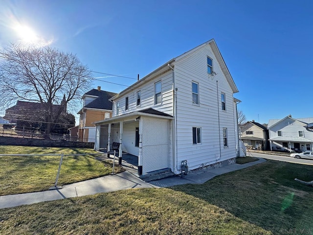 view of side of home featuring a lawn and fence