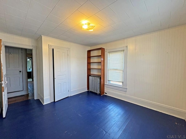 unfurnished bedroom with dark wood-type flooring, radiator, baseboards, and a closet