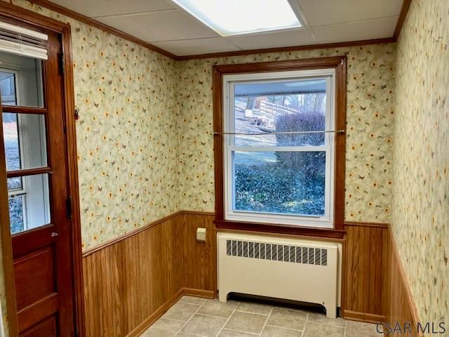 interior space with ornamental molding, radiator, wainscoting, wallpapered walls, and light tile patterned floors