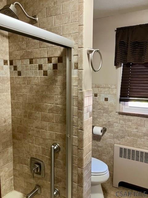 full bath featuring toilet, tile walls, radiator heating unit, and tile patterned flooring