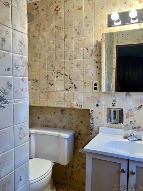 bathroom with toilet, tile walls, and vanity