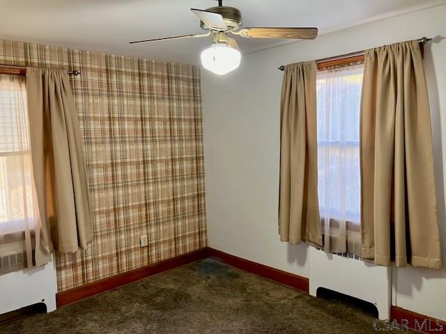 empty room with wallpapered walls, carpet, baseboards, and ceiling fan