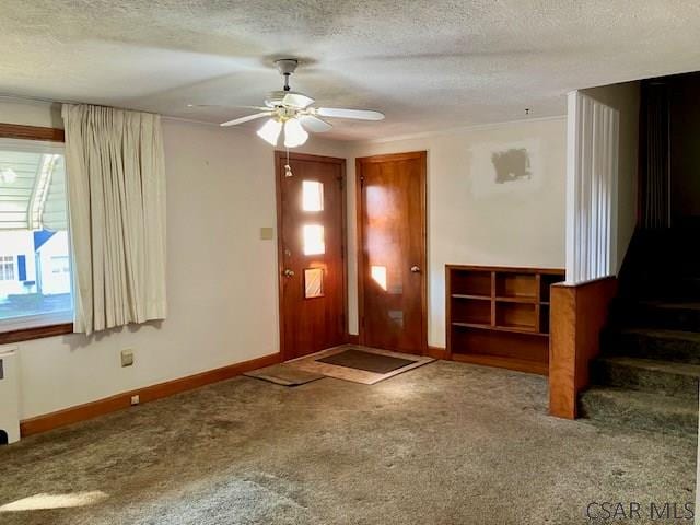 carpeted foyer entrance featuring ceiling fan, baseboards, stairway, radiator heating unit, and a textured ceiling