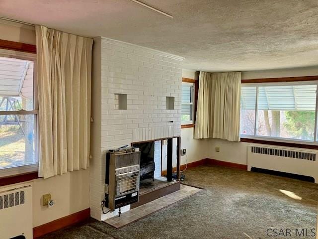 unfurnished living room with heating unit, radiator, a fireplace, and a textured ceiling