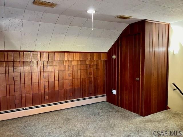 additional living space featuring vaulted ceiling, carpet, wood walls, and a baseboard radiator